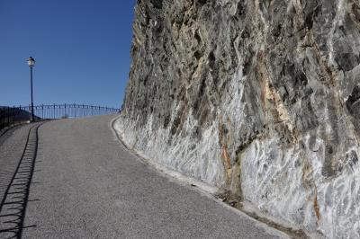 photograph “IV.2023 — Brain mass (II)” par David Farreny — www.farreny.net — Andorre, Andorra, Canillo, rocher, rock, montagne, mountain, masse, mass, rambarde, guardrail, métal, metal, route, road, bitume, blacktop, asphalte, asphalt, lampadaire, lamp, ciel, sky, ombre, shadow, caniveau, gutter, mur, wall, paroi