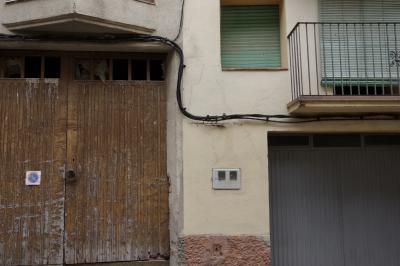 photograph “VI.2023 — Faces of home, 195” par David Farreny — www.farreny.net — Espagne, España, Espanya, Spain, Catalogne, Cataluña, Catalunya, Catalonia, Lérida, Lleida, Alt Urgell, Organyà, ville, city, bourgade, town, rue, street, maison, house, portail, gate, bois, wood, ciment, cement, fenêtres, windows, balcon, balcony, rambarde, guardrail, métal, metal, câbles, cables, fils, wires, garage, stores, blinds, boîtier électrique, electric box