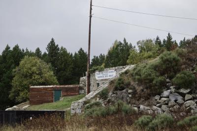photograph “X.2023” par David Farreny — www.farreny.net — France, Occitanie, Pyrénées-Orientales, Font-Romeu-Odeillo-Via, Font-Romeu, forêt, forest, station d'épuration, wastewater treatment plant, inscription, sign, plaque, plate, Ville de Font-Romeu, Service des eaux, eau, water, poteau, post, pole, bois, wood, local, shed, pierre, stone, colline, hill, arbres, trees, herbe, grass, câbles, cables, fils, wires, ciel, sky, gris, gray