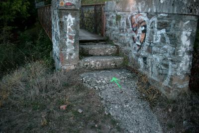 photograph “X.2011” par David Farreny — www.farreny.net — France, passerelle, footbridge, pont, bridge, marches, steps, muret, low wall, pierre, stone, ciment, cement, métal, metal, flèche, verte, green, arrow, entretoises, cross, struts, ties, graffitis, graffiti, herbe, grass, arbre, tree, Occitanie, Aveyron, Rouergue, Olemps