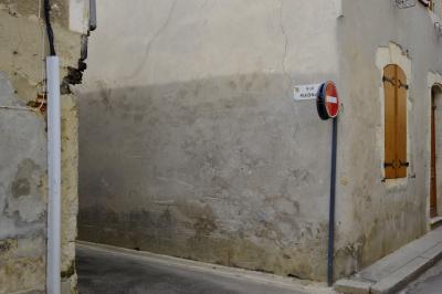 photograph “III.2021” par David Farreny — www.farreny.net — France, Occitanie, Gascogne, Gascony, Gers, Éauze, rue, street, Magnan, bitume, blacktop, asphalte, asphalt, coin, corner, angle, plaque, plate, panneau, sign, routier, roadsign, sens interdit, one way, fenêtre, window, porte, door, volets, shutters, bois, wood, câbles, cables, fils, wire, pierre, stone, ciment, cement, trottoir, pavement, mur, wall, gris, grey, gray
