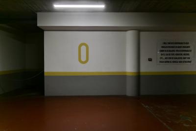 photograph “X.2023 — Zero” par David Farreny — www.farreny.net — Andorre, Andorra, Canillo, parking, car park, souterrain, underground, béton, concrete, mur, wall, néon, neon, lumière, light, colonne, column, pilier, pillar, panneau, board, message, catalan, numéro, number, chiffre, digit, 0, zéro, zero, chaîne, string, rouge, red, sol, floor