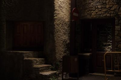 photograph “VIII.2023 — At night” par David Farreny — www.farreny.net — Andorre, Andorra, Canillo, soir, evening, nuit, night, rue, street, maison, house, pierre, stone, enduit, roughcast, pénombre, darkness, sombre, dark, panneau, sign, routier, roadsign, sens interdit, one way, marches, steps, escalier, stairs, porte, door, verre, glass, vitre, barrière, guardrail, métal, metal, poubelle, bin, trash, affiche, poster, bill, Sant Roc, volets, shutters, bois, wood, lumière, light