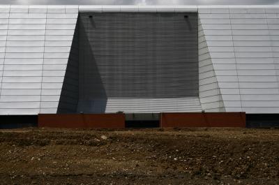 photograph “VI.2008” par David Farreny — www.farreny.net — France, Occitanie, Haute-Garonne, Toulouse, Zénith, salle de spectacle, performance hall, bâtiment, immeuble, building, mur, wall, béton, concrete, terrain, ground, clôture, fence, métal, metal, terre, earth, sol, soil, ombre, shadow, renfoncement, recess, cailloux, stones