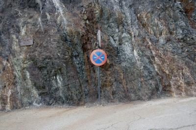 photograph “IX.2023” par David Farreny — www.farreny.net — Andorre, Andorra, Canillo, montagne, mountain, mur, paroi, wall, rocher, roche, rock, route, road, plaque, plate, carrer del Tosqué, panneaux, signs, routiers, roadsigns, interdiction de stationner, no parking, flèches, arrows, droite, right, gauche, left, stop, bitume, blacktop, asphalte, asphalt, métal, metal, traces, dépression, depression
