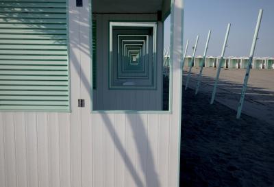 photograph “V.2022” par David Farreny — www.farreny.net — Italie, Italia, Italy, Vénétie, Veneto, Venise, Venice, Venezia, Venexia, Lido, plage, beach, cabines, cabins, bois, wood, poteaux, posts, poles, métal, metal, sable, sand, charnières, hinges, arbre, tree, ombre, shadow, cadres, frames, fenêtres, windows, profondeur, depth, vide, empty, emptiness