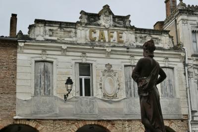 photograph “V.2025 — Let\'s have a coffee” par David Farreny — www.farreny.net — France, Occitanie, Gascogne, Gascony, Lomagne, Fleurance, ville, city, place de la République, maisons, houses, façade, pierre, stone, beige, brique, brick, fenêtres, windows, volets, shutters, bois, wood, lampe, lamp, enseigne, sign, café, statue, L'Été, Summer, Les Quatre saisons, The Four Seasons, Albert-Ernest Carrier-Belleuse, XIXe siècle, 19th century, 1895, femme, woman, fontaine, fountain, silhouette, sculpture, gouttière, drainpipe, cheminée, chimneys, bâche, sheet, arcades, arches, archs, fronton, pediment, art