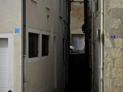 photograph “II.2017 — Faces of home, 96” par David Farreny — www.farreny.net — France, ville, immeubles, buildings, maisons, city, houses, rue, street, ruelle, alley, fenêtres, windows, portail, gate, porte, door, voitures, cars, étroit, narrow, numbers, plates, numéros, plaques, 75, 77, gouttières, drainpipes, angles, coins, corners, pierre, stone, Occitanie, Gascogne, Gers, Auch