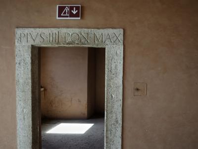 photograph “V.2017” par David Farreny — www.farreny.net — Italie, Italy, Italia, Latium, Lazio, Rome, Roma, château, Saint-Ange, castel, Sant'Angelo, castle, Holy Angel, porte, door, pierre, stone, inscription, writing, lettres, letters, capitales, capital, PIUS IIII PONT MAX, Pie IV, Pius IV, pape, pope, pontifex maximus, panneau, sign, issue de secours, emergency exit, lumière, light, flèche, arrow, soleil, sun, mur, wall