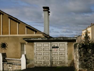 photograph “I.2012 — Faces of home, 55” par David Farreny — www.farreny.net — France, domicile, home, maison, house, garage, porte, door, bois, wood, ciment, cement, pierre, stone, cheminées, chimneys, aluminium, aluminum, métal, metal, œil-de-bœuf, bull's-eye, fenêtre, window, grille, railings, plaque d'immatriculation, number plate, registration plate, license plate, panneau, sign, mur, wall, arbre, tree, immeubles, buildings, délabrement, decay, soir, evening, hiver, winter, nuages, clouds, volets, shutters, fil, wire, câble, cable, Occitanie, Aveyron, Rouergue, Rodez