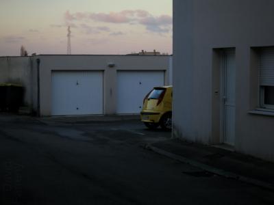 photograph “XII.2013 — Evening without regret” par David Farreny — www.farreny.net — France, Occitanie, Rouergue, Aveyron, Olemps, immeuble, bâtiment, building, appartement, flat, porte, door, fenêtre, window, portails, gates, voiture, car, jaune, yellow, Fiat, Punto, poubelle, trash, bin, soir, evening, hiver, winter, ciel, sky, nuages, clouds, pylône, électricité, electricity, post, pole, bitume, blacktop, asphalte, asphalt, trottoir, pavement, béton, concrete