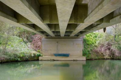 photograph “III.2021 — Concrete postcard” par David Farreny — www.farreny.net — France, pont, bridge, béton, concrete, rivière, river, eau, water, rive, bank, nature, barque, bateau, boat, small boat, bois, wood, arbres, trees, vert, green, bleu, blue, printemps, spring, springtime, corde, rope, panneau, sign, carte postale, postcard, Occitanie, Gascogne, Gers, Valence-sur-Baïse